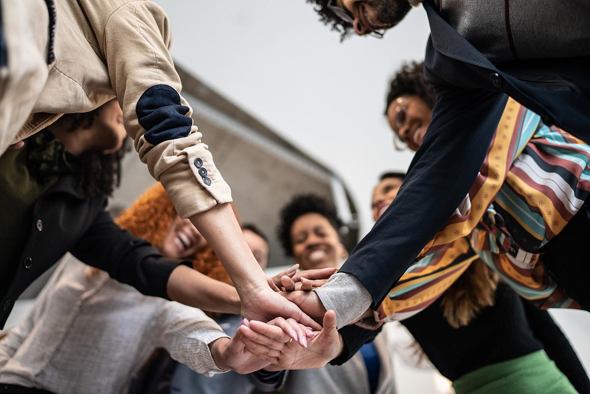 different types of people standing around in a circle with their hands stacked for teamwork 