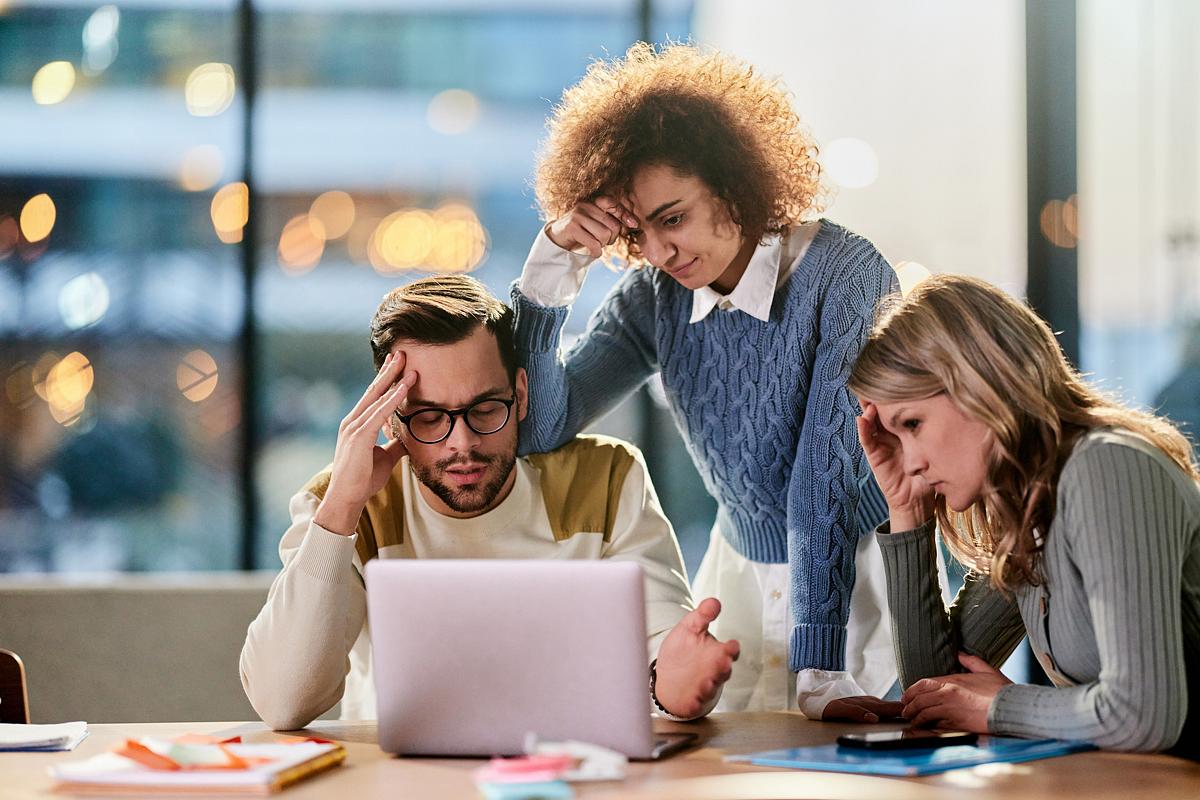marketing team at a table frustrated about results on laptop