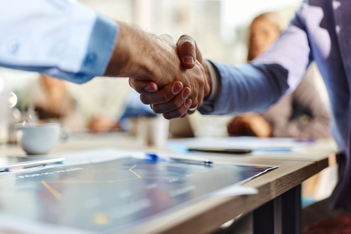 two men shaking hands over business documents 